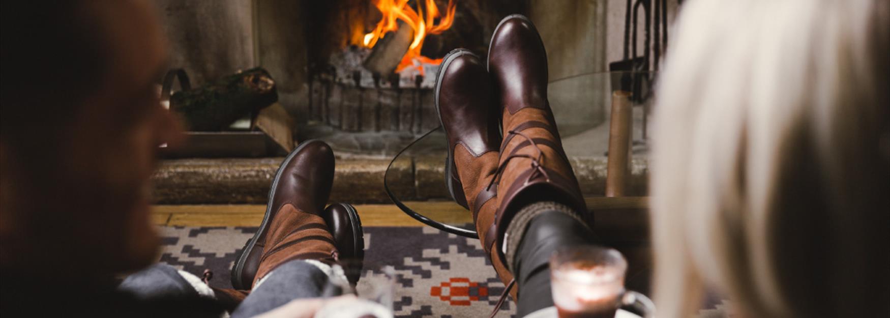 Couple enjoying a drink in front of a roaring fire