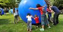 Family rolling a huge inflatable ball at one of Cheltenham's festivals