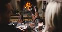 Couple enjoying a drink in front of a roaring fire